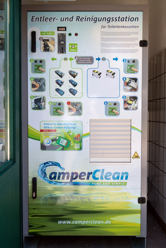 Eine CamperClean-Maschine zum Entleeren und Reinigen von Toilettenkassetten, die auf der Vorderseite Anweisungen, Zahlungsinformationen und die Website des Unternehmens anzeigt.