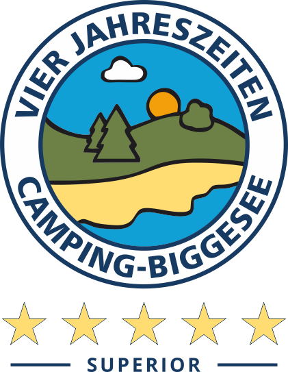 Rond logo met een landschap van heuvels, bomen, water, een wolk en een opkomende zon. De tekst luidt Vier Jahreszeiten Camping-Biggesee. Vijf sterren en Superior staan onder het logo.